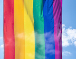 Obraz premium Rainbow flag in sunshine against blue sky