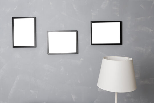 three blank black photo frames on a gray wall in the interior