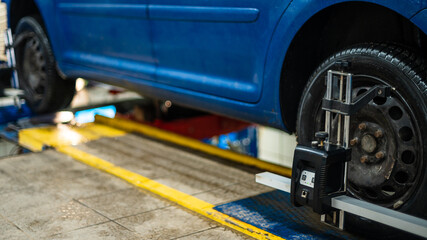 Close-up of a tire clamped by a leveler that passes the automatic alignment of the wheels in the...