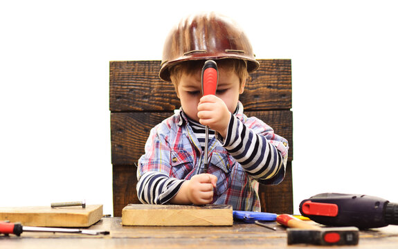 Kid twists bolt with screwdriver. Child Boy in workshop. Little Repairman. Repair tool.