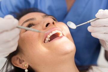Close up view of dentist treating teeth of hispanic woman in dentist office