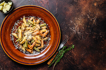 Seafood color Penne pasta in cream sauce on a plate. Dark background. Top view. Copy space