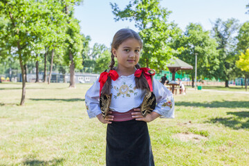 Serbian folklore, smiling cute little girl in traditional Serbian clothing. Outdoor portrait