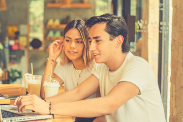 YOUNG COUPLE WATCHING THE COMPUTER IN A COFFEE SHOP 
