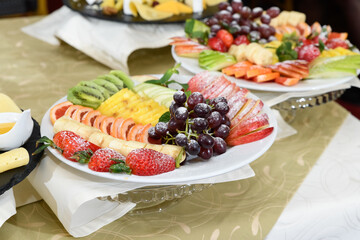 Close up view of tray with various fruits like apples, coconut, oranges, grape, watermelon, plums on the serving table for the party.