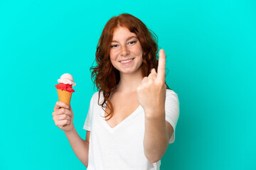 Teenager reddish woman with a cornet ice cream isolated on blue background doing coming gesture