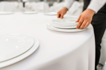 The waiter in the restaurant serves the dining table. Close up restaurant setting. Out of focus, blur photo