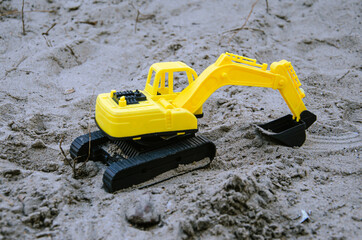 Yellow and black color toy excavator miniature on the ground with selective focus