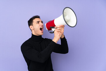 Young caucasian handsome man with turtleneck sweater isolated on purple background shouting through a megaphone