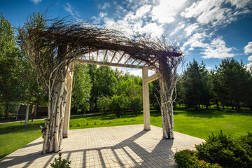 Pergola in a garden with fresh lawn around. Patio place