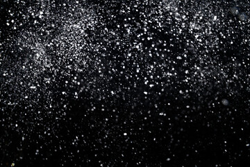 Naklejka na ściany i meble Many snowflakes in blur on black background. Snowfall layer for winter photography