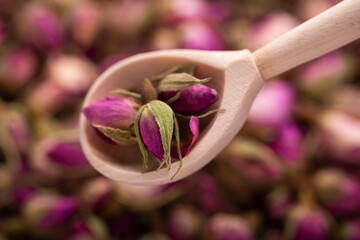 Dried roses. Rosebuds for decoctions. Dried rosebuds in a wooden spoon close-up.