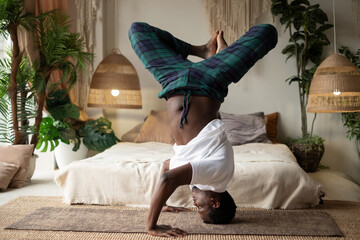 Young african fitness sportsman in yoga position on head working