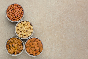 Nuts of different varieties, top view. The mixed nuts lie in bowls on a stone countertop. For...