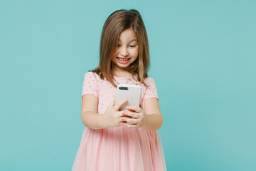 Little fun cute kid girl 5-6 years old wears pink dress hold in hand using mobile cell phone isolated on pastel blue color background child studio portrait. Mother's Day love family lifestyle concept.