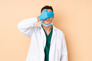 Young dentist man holding tools isolated on beige background covering eyes by hands. Do not want to see something