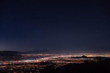 Vertical shot of a city from afar at night with bright lights and a dark sky above
