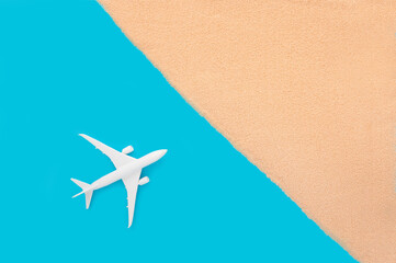Fototapeta na wymiar Creative summer traveling concept with beach sand and toy airplane on pastel blue background