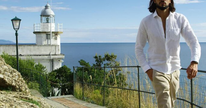 Man walking and watching at the a lighthouse. We can see the Mediterranean Sea in the background under the sunlight - Red Camera 4K