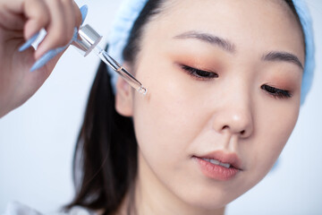 Asia Korean girl takes care of the skin of the face with a serum from a transparent glass pipette to moisturize and soften the skin of the face and maintain natural beauty.