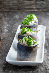 Appetizing pickled herring rolls stuffed with cream cheese and egg mass served on white plate