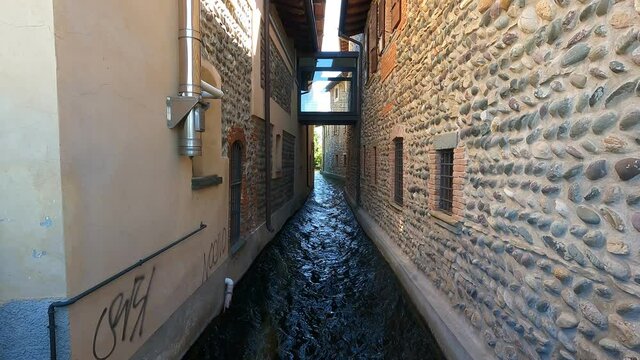 The water of a canal flows fast between the walls of the houses