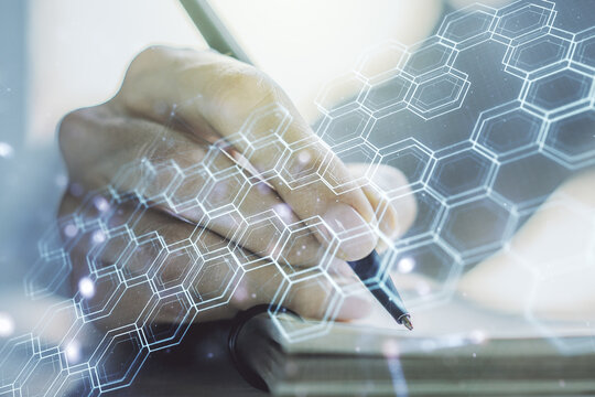 Creative concept of wireless technology with hexagon hologram and woman hand writing in notebook on background. Big data and database concept. Multiexposure