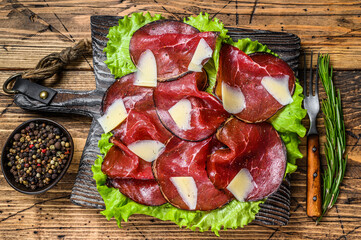 Italian Antipasti Bresaola meat cut with green salad and Parmesan. wooden background. Top view