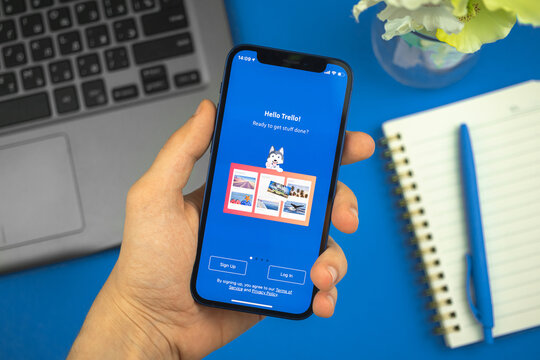 Kharkov, Ukraine - May 28, 2021: Man use Trello app on the screen of Apple iPhone 12