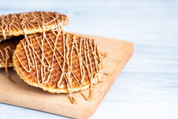 Traditional local authentic Dutch Netherlands sweet fresh homemade tasty stack brown golden waffle melt salted caramel honey syrup for dessert in cafe with hot warm coffee milk tea call Stroopwafel