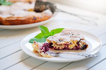 Piece of homemade simple pie with fresh red raspberries and black mulberry on a light background. Summer berry dessert. close up