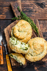 Baked spiral filo pastry puff with feta cheese and spinach. Dark wooden background. Top view