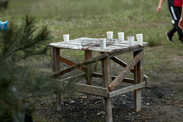 Disposable white glasses mockups on an old wooden table outside. Leisure activity concept. High quality photo