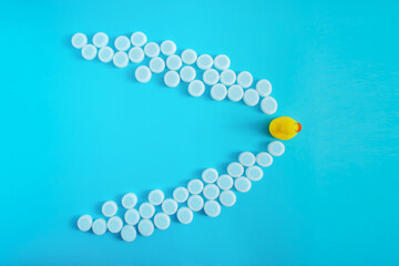 Yellow rubber duck floats on a blue surface through plastic waste pollution. White and grenn bottle caps. Polluted environments.