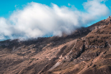 High-altitude landscape with big white clouds over the mountains.