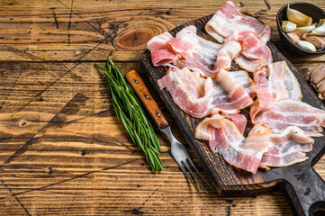 Smoked pork bacon slices on a wooden cutting board. wooden background. Top view. Copy space