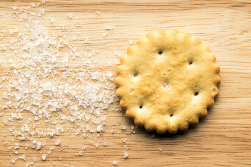 Salted cracker and salt on a wooden surface