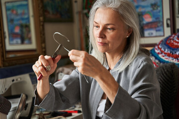 Female hats maker shape the hat in her workshop, while holding forceps and carcass
