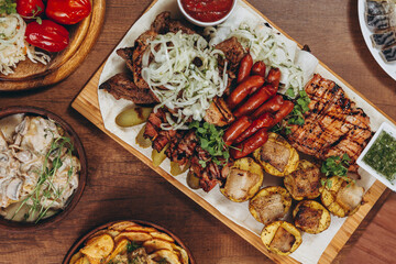 assorted various meat and vegetable dishes laid out on the village board for serving in a restaurant of Ukrainian cuisine