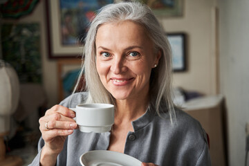 Woman drinking her morning tea and looking at the camera