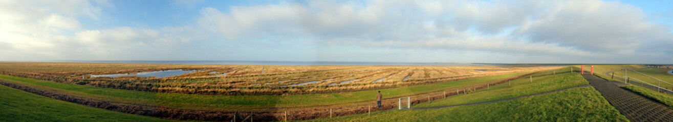 Obraz premium Panorama View From The Dike To The North Sea In The National Park Wadden Sea In PIlsum East Frisia On A Sunny Summer Day With A Clear Blue Sky And A Few Clouds