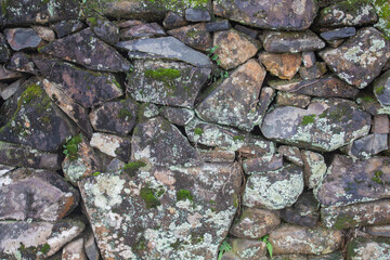 an old manmade stone wall with moss on it