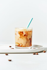 Iced cold brew coffee with coconut milk and mocha in glass with straw on white background with copy space. Menu mockup. Summer cold refreshing drink concept.