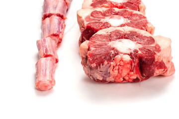 Raw uncooked beef oxtail cut into portions on white isolated background. Butcher craft. Meat industry product. Soup and stew ingredient