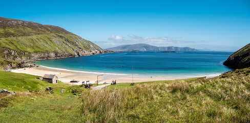 Panorama image of Keem beach, Achill island in county Mayo, Ireland, warm sunny day. Clear blue sky and water of the Atlantic ocean.