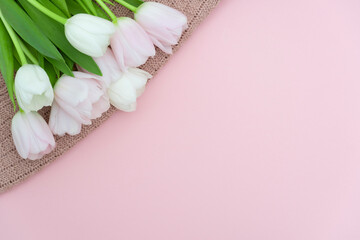 Bouquet of pink pastel tulips on pink knit sweater background, top view of pink tulips bouquet for womans Day, spring flowers concept.