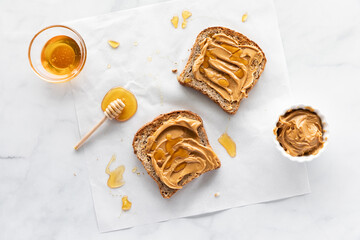 Two pieces of toast with peanut butter and honey spread on top and a mess of honey all around. - obrazy, fototapety, plakaty