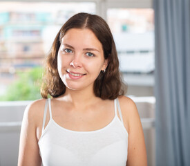 Attractive young woman standing at home interior, posing on camera