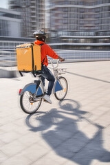 Obraz premium Courier with yellow backpack driving bike and coming to the client with parsels
