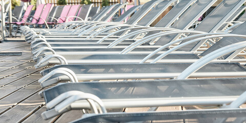 sun loungers stand in a row waiting for vacationers by the sea by the pool